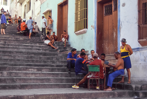 Santiago, Cuba - aug 2001: in the evening, when the air becomes a little cooler, the inhabitants of a neighborhood gather on the street for a game of cards, to talk and to enjoy the quiet and cool of the evening.