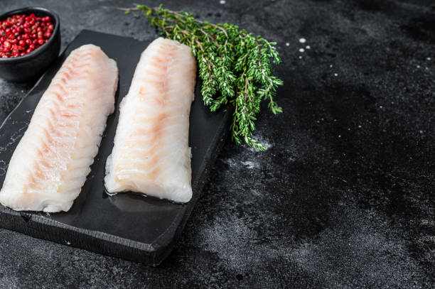 istock Raw cod loin fillet fish on marble board. Black background. Top view. Copy space 1317691137