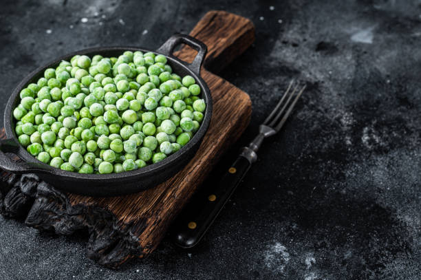 istock Fresh Frozen green peas in a pan. Black background. Top view. Copy space 1317692056