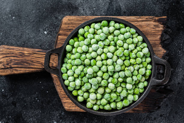 istock Fresh Frozen green peas in a pan. Black background. Top view 1317692071