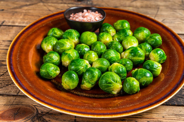 istock Cooked Brussels green sprouts cabbage in a rustic plate with salt. wooden background. Top view 1317692118