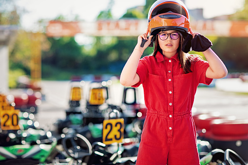Portrait of girl putting on her helmet at the go-cart track
