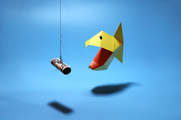 Piranha pecks on hook with bait dollar. Origami fish on blue background Concept of greed to rapid loan, business and finance. Piranha pecks on hook with bait dollar. Origami fish on blue background with copy space making money origami stock pictures, royalty-free photos & images