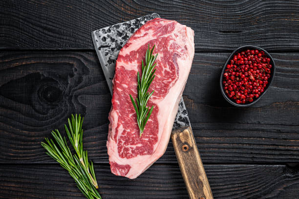 fresh raw new york strip beef steak on a butcher meat cleaver. black wooden background. top view - beef sirloin steak raw loin imagens e fotografias de stock