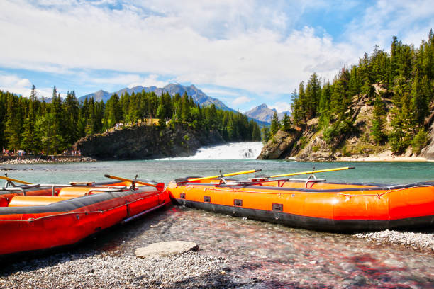 Rafting Boats on Bow River in Canadian Rockies of Banff National Park Rafting boats on the edge of Bow River with Bow Falls and the Canadian Rockies of Banff National Park in the background. bow river stock pictures, royalty-free photos & images