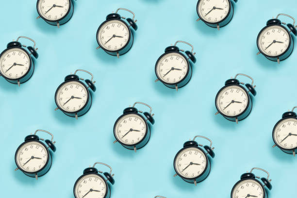 青い背景に黒目覚まし時計の創造的なレイアウト。最小限のコンセプト - deadline time clock urgency ストックフォトと画像