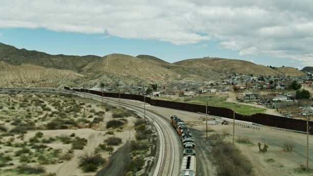 istock Freight Train on Tracks in New Mexico Alongside US/Mexico Border Wall - Drone Shot 1317711678