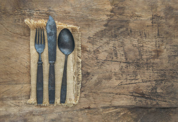 Rustic ancient vintage cutlery in a sackcloth on rustic wooden table. Copy space, Selective focus.
