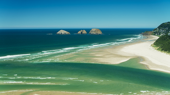 Aerial view of the beach at Netarts Bay, Oregon on a sunny summers day, with the famous Three Arch Rocks in the distance.