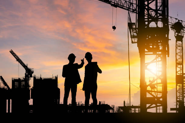 istock Silhouette of Engineer and worker checking project at building site background, construction site at sunset in evening time 1317714881