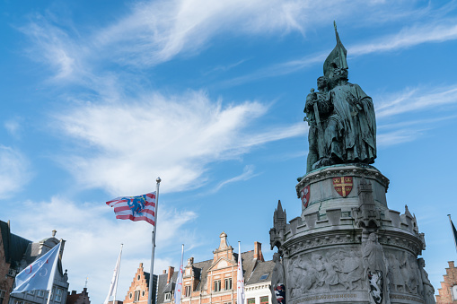 The Jan Breydel and Pieter de Coninck statue located in the historical city center and Market Square (Markt) in Bruges (Brugge), with beautiful nice cloud blue sky Belgium on a sunny day