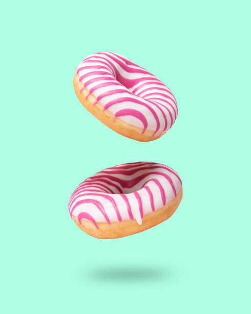 istock Two pink glazed  donut flying on neo mint background. Levitation concept food. 1317724021