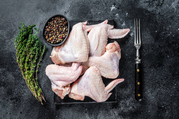 istock Raw chicken wings Poultry meat on a marble board. Black background. Top view 1317725805