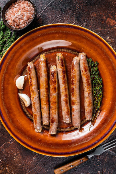 istock Grilled beef and pork meat sausage on rustic plate with thyme. Dark background. Top view 1317726662