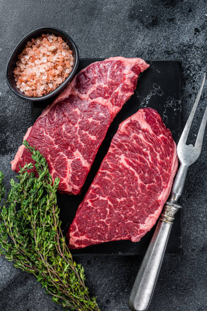 istock Fresh Raw Denver steak Marble beef meat with herbs. Black background. Top view 1317726744
