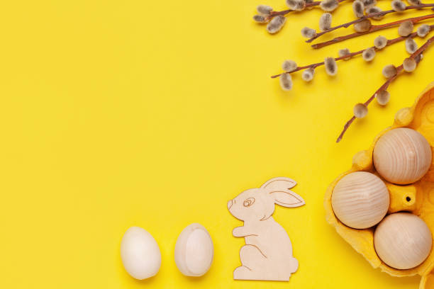 istock Wooden eggs, rabbit and branch trees. Easter zero waste. Top view. Yellow background 1317728614