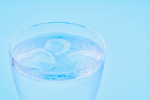 istock A cold glass of ice with water drops on a light blue background 1317729303