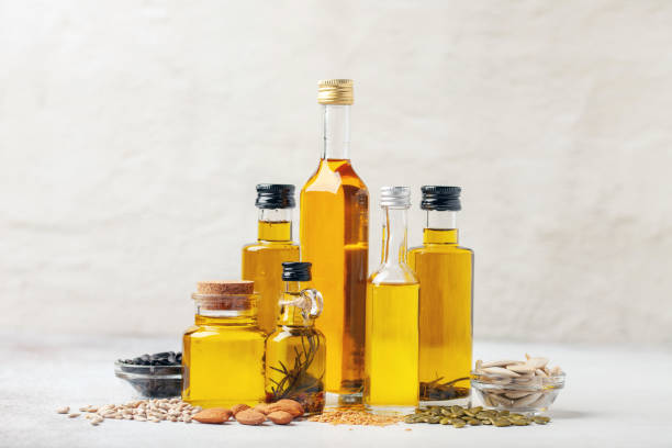 varios aceites vegetales y de nuez en botellas sobre un fondo brillante. - aceite de oliva fotografías e imágenes de stock