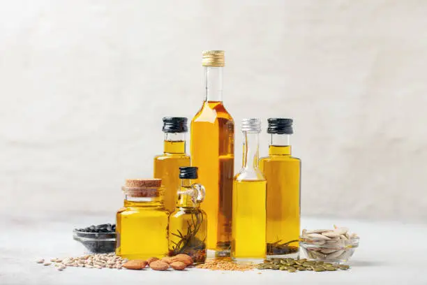 Photo of Various vegetable and nut oil in bottles on a bright background.