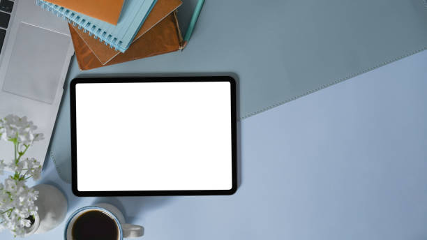 istock Top view of stylish workspace with digital tablet, coffee cup, notebook and copy space on blue background. 1317730448