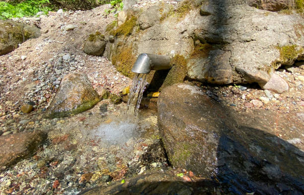 A fresh and cool spring flows from the ground. Cool and delicious spring water. Natural underground water source.