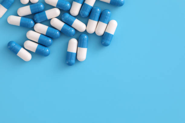 istock pills capsules isolated on blue background 1317733403