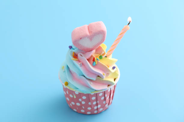 istock Colorful cupcake with candle isolated in blue background 1317733413