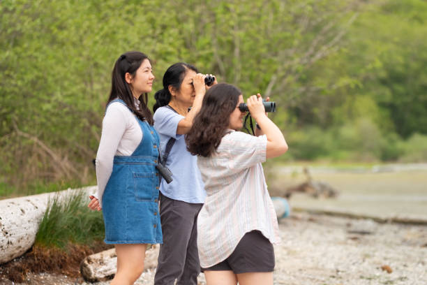 Multi-Ethnic Family, Mother and Daughters Birdwatching on Remote Rugged Beach