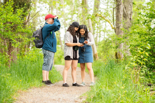 istock Family Birdwatching in Forest, Sisters Checking Smartphone Together 1317734565