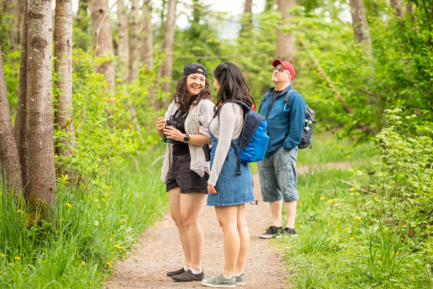 istock Sisters Laughing While Walking and Birdwatching in Forest with Father 1317734614