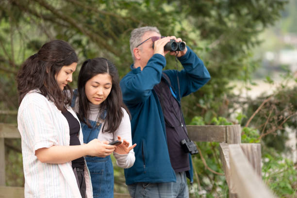 Multi-Racial Family Using Binoculars and Bird Watching App on Smartphone