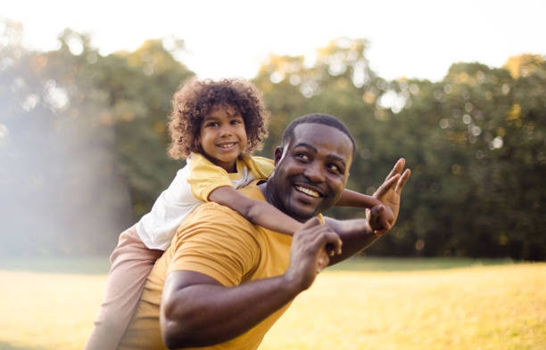 African American father and daughter having fun outdoors.
