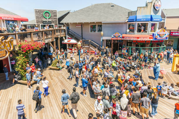 Crowd of people at Pier 39 San Francisco, USA SAN FRANCISCO, CALIFORNIA, USA - July 24, 2018: Crowd of people at Pier 39 on a sunny day. Popular landmark and commercial area overcrowded with people. fishermans wharf san francisco photos stock pictures, royalty-free photos & images