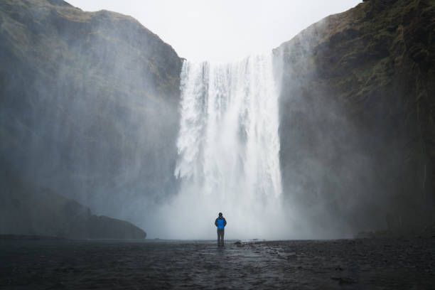 istock Man standing in front of waterfall 1317740899