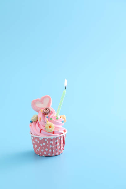 istock Colorful cupcake with candle isolated in blue background 1317742472