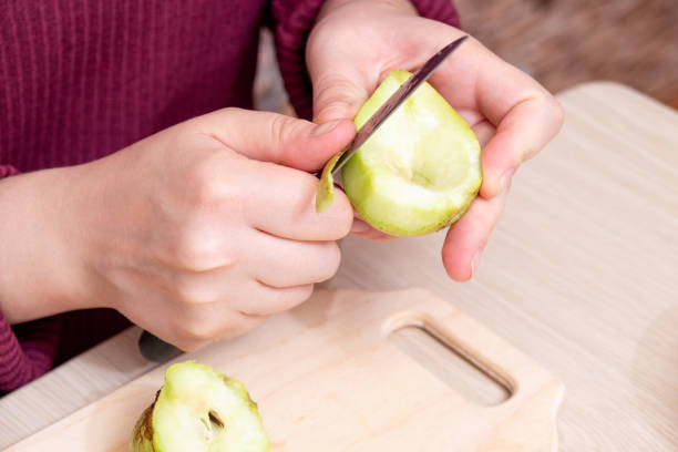 istock Peeling the pear halves from the skin with a knife. Selective focus. 1317742498