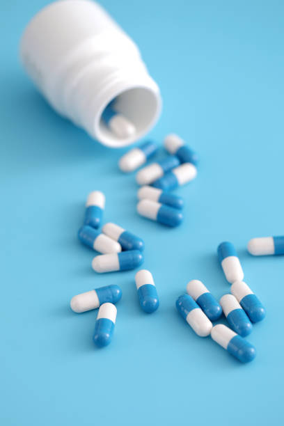 istock pills capsules with bottle isolated on blue background 1317742530