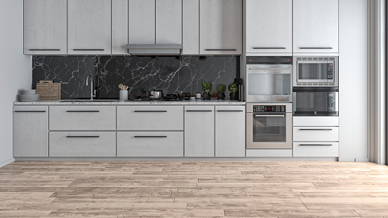 Empty modern kitchen on hardwood floor with white wooden kitchen cabinets, black and white marble background and a large window on a side. Utensils, potted herbs, spices and stoves on kitchen counter. 3D rendered image.