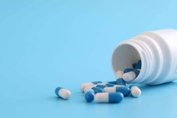istock pills capsules with bottle isolated on blue background 1317742779