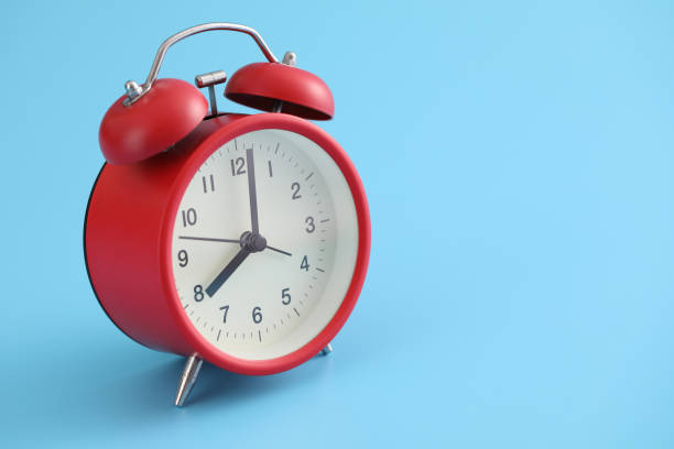 istock Red retro alarm clock isolated on a blue background 1317742782