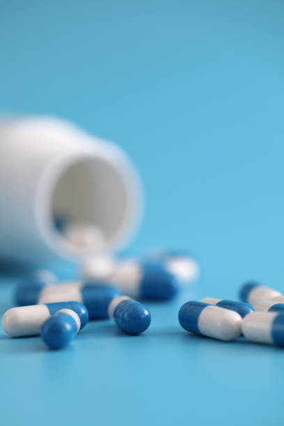 istock pills capsules with bottle isolated on blue background 1317744168