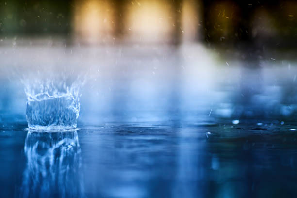 small splashing crown from rain's droplet when fall down on the floor in rainy day with blue shade color tone and golden sun light behind