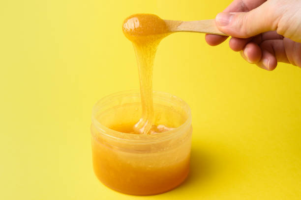 istock Liquid sugar wax in jar with spatula in hand close 1317746911