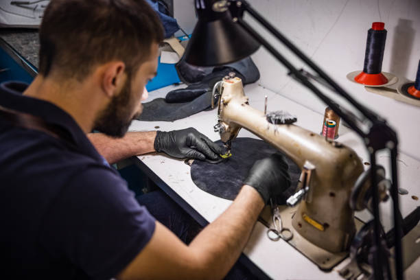istock Young man stitching a piece of leather on special sewing machine 1317746974