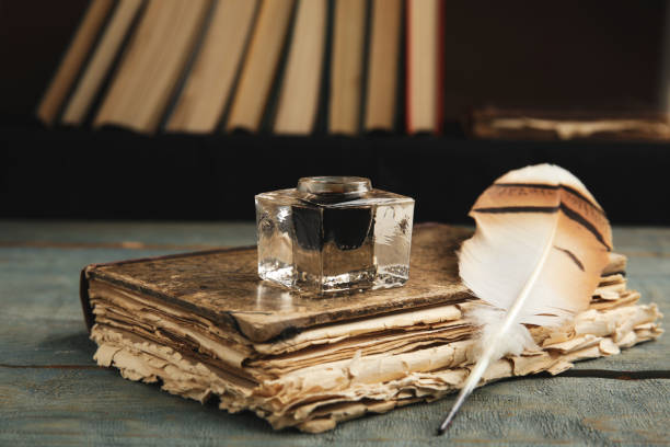 istock Feather pen, inkwell and book on blue wooden table 1317748432