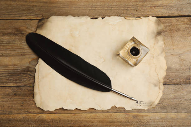 istock Feather pen, inkwell and parchment on wooden table, top view 1317748466