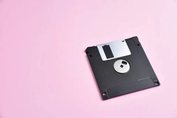 Floppy disk on pink background. Retro computer diskette