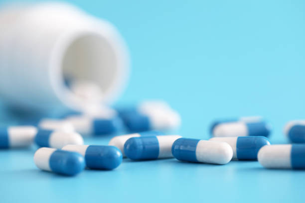 istock pills capsules with bottle isolated on blue background 1317758872