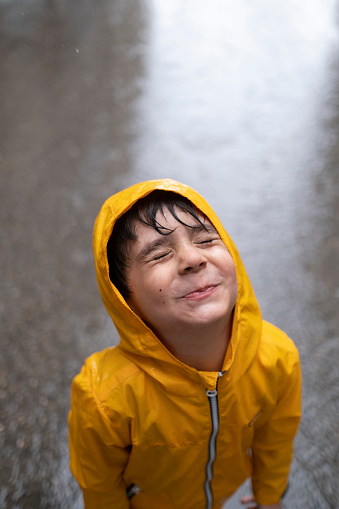 Adorable little boy playing at rainy day