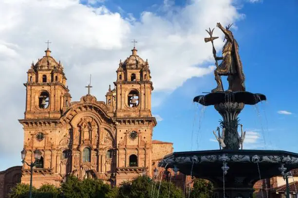 Statue of Inca Pachacutec on fountain and catholic church on Plaza de Armas, Cusco or Cuzco town, Peru